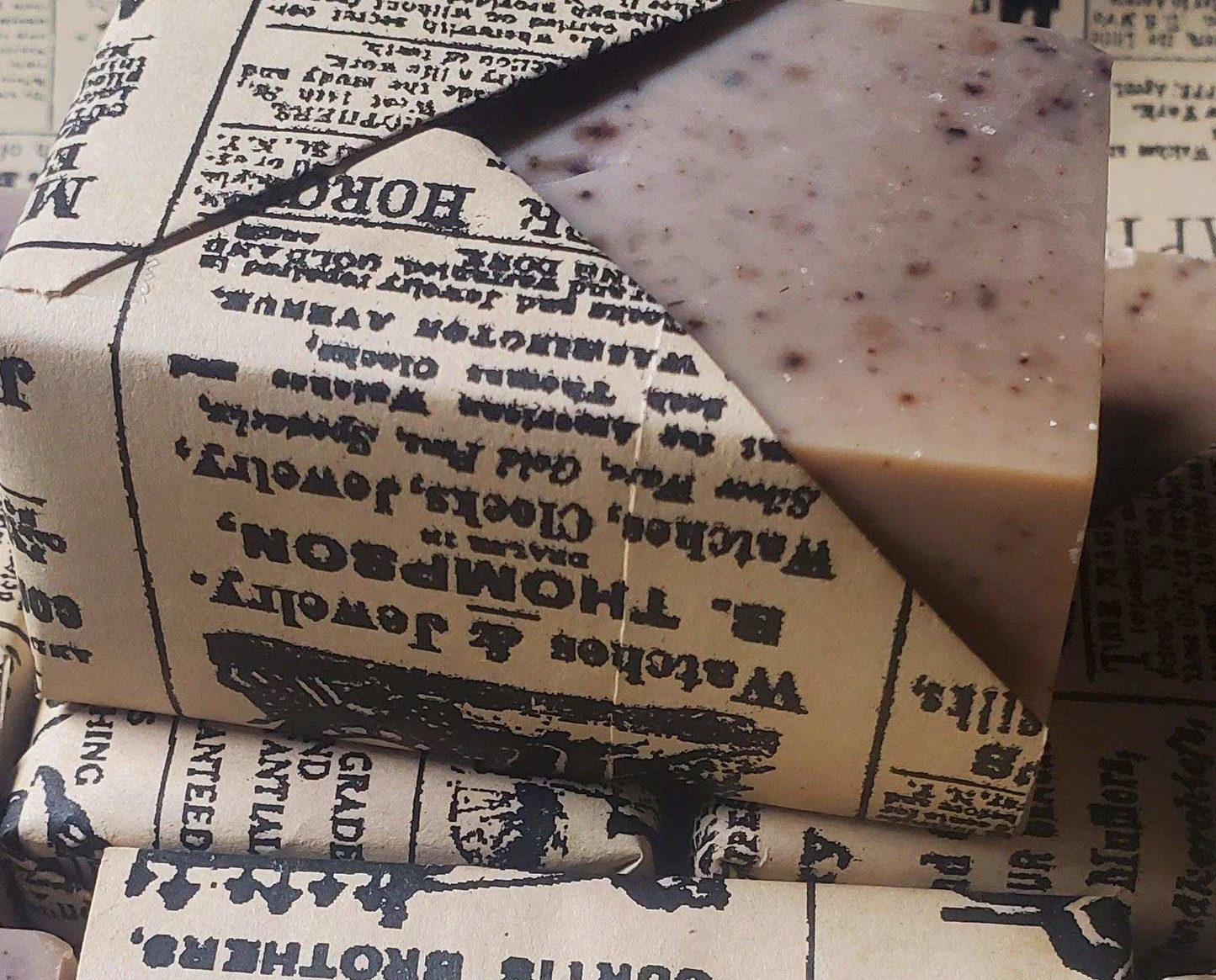 Bar of goat milk soap on top of a newspaper-textured box