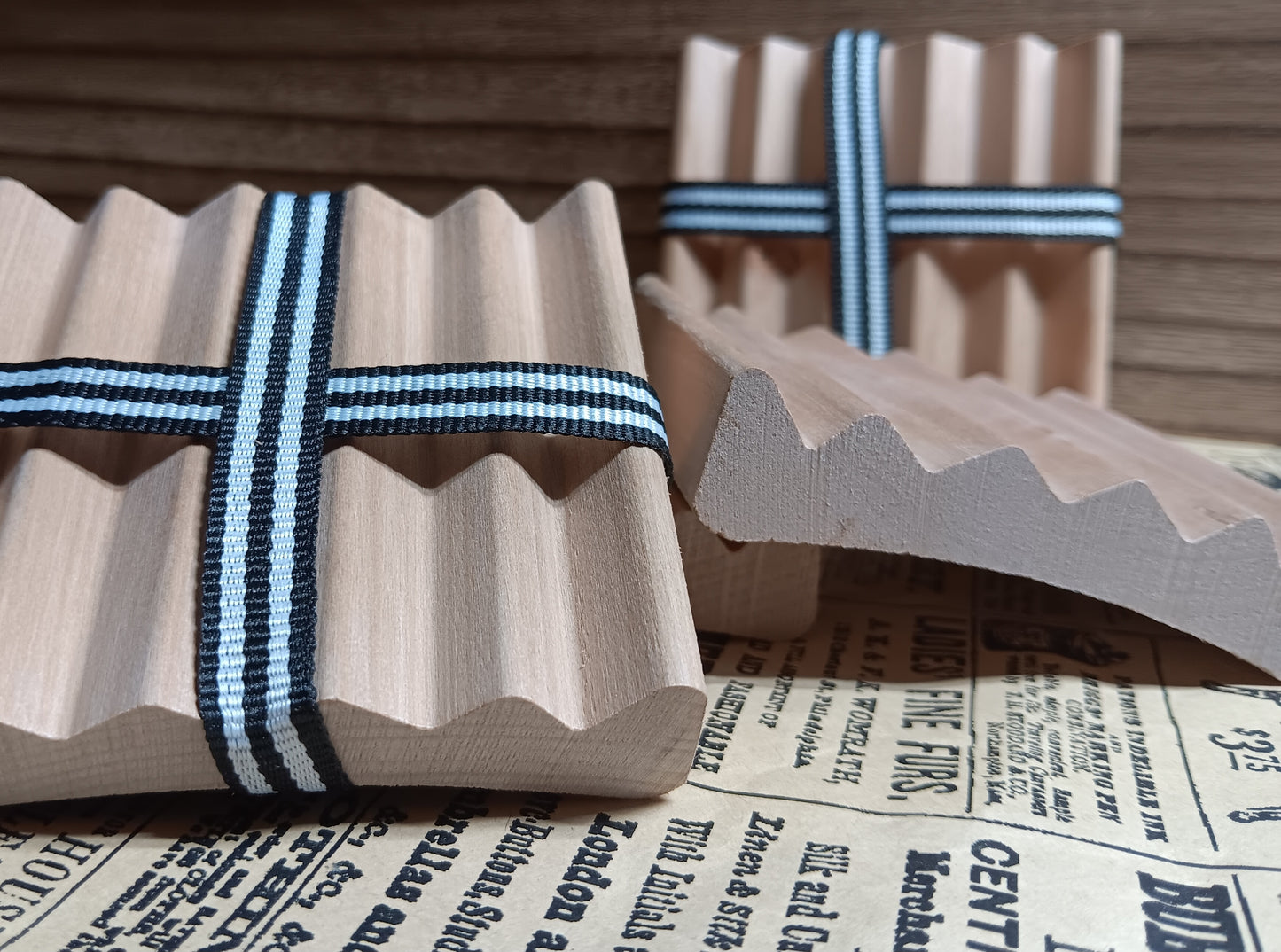 Wooden red alder soap dishes ribbons on a newspaper background