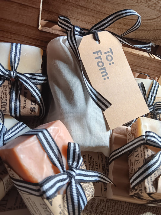 Bar of soap with a black and white striped ribbon and a 'To: From:' tag on a wooden surface.