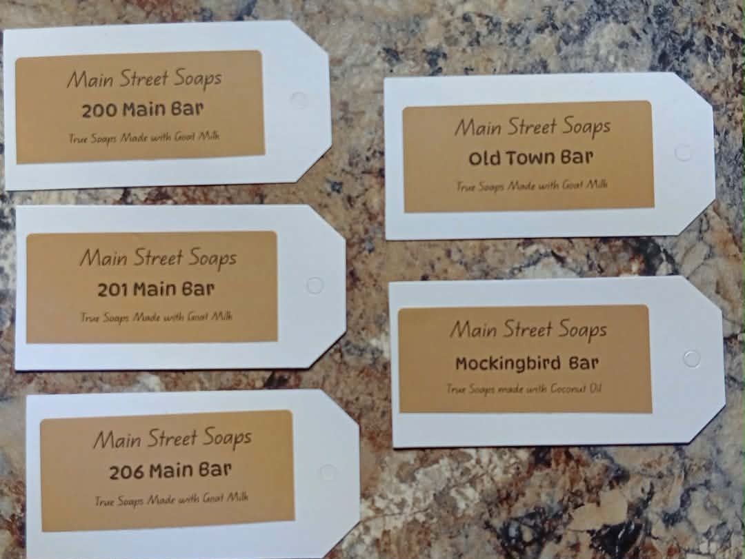 Five Custom Main Street Soaps product tags on a textured surface