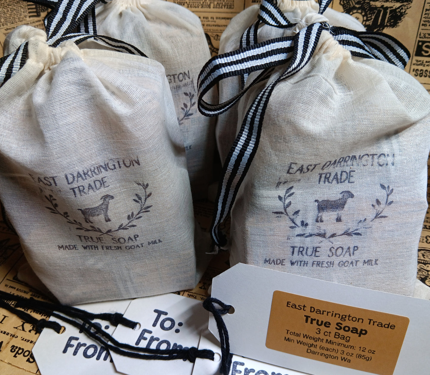 Four bags of East Darrington Trade True Soap with labels and tags on a textured surface.