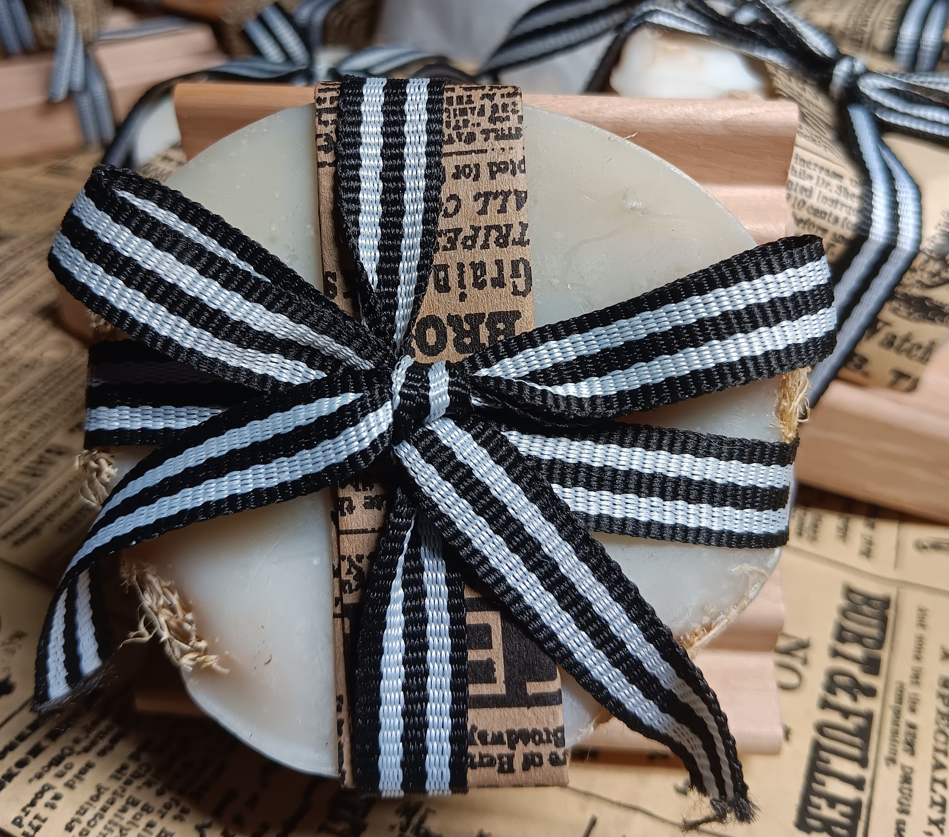 Decorative goat milk soap with a black and white striped bow on a newspaper background