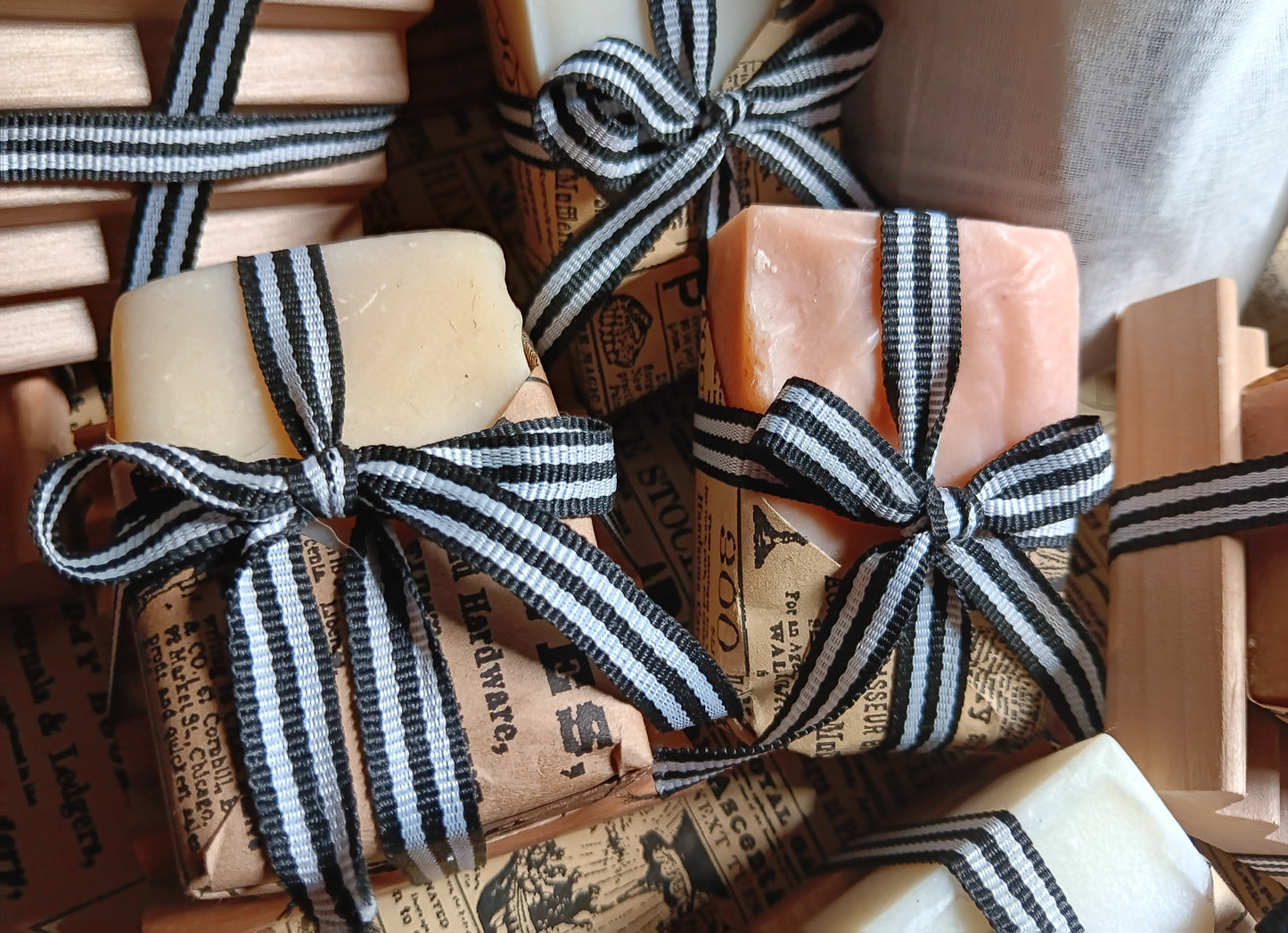 Bar of goat milk soaps tied with black and white striped ribbons on a rustic background
