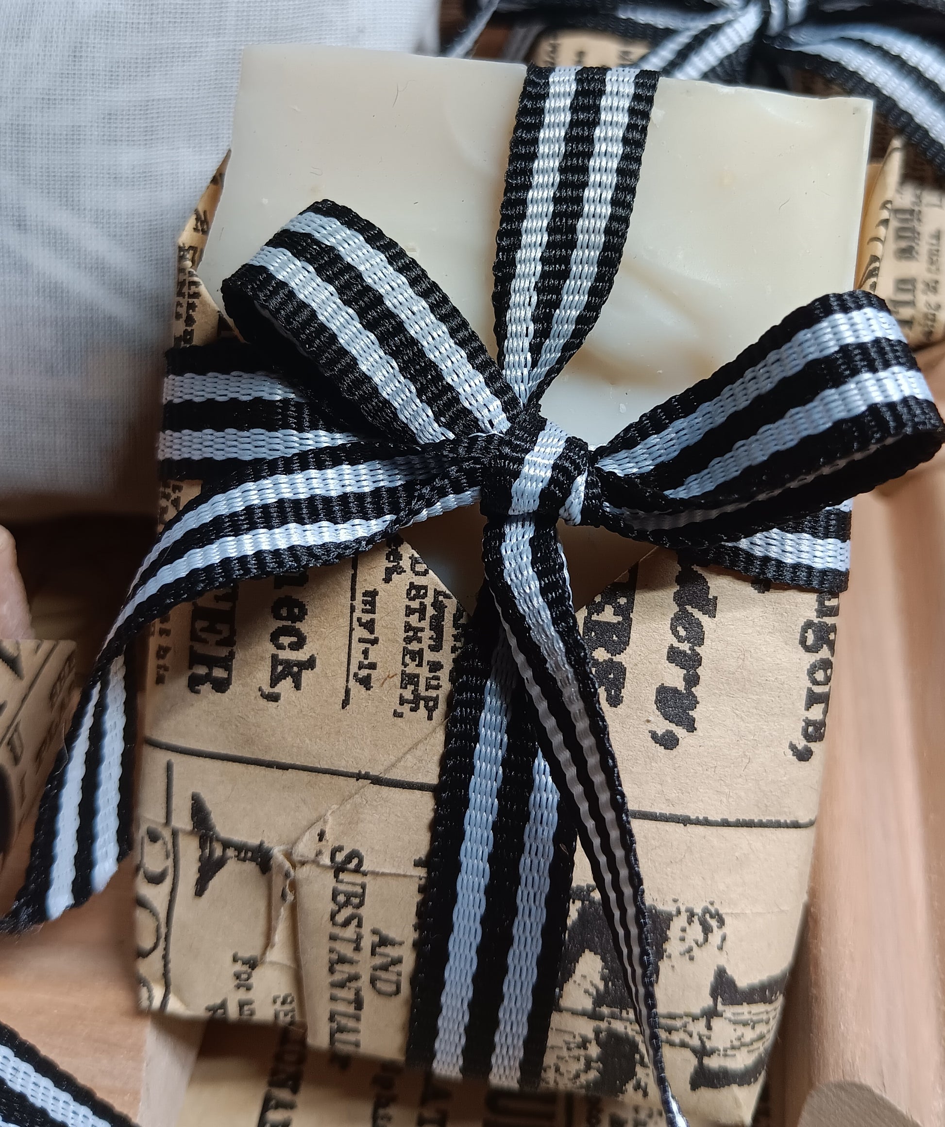 Gift wrapped cold processed soap bar in brown paper with a black and white striped ribbon