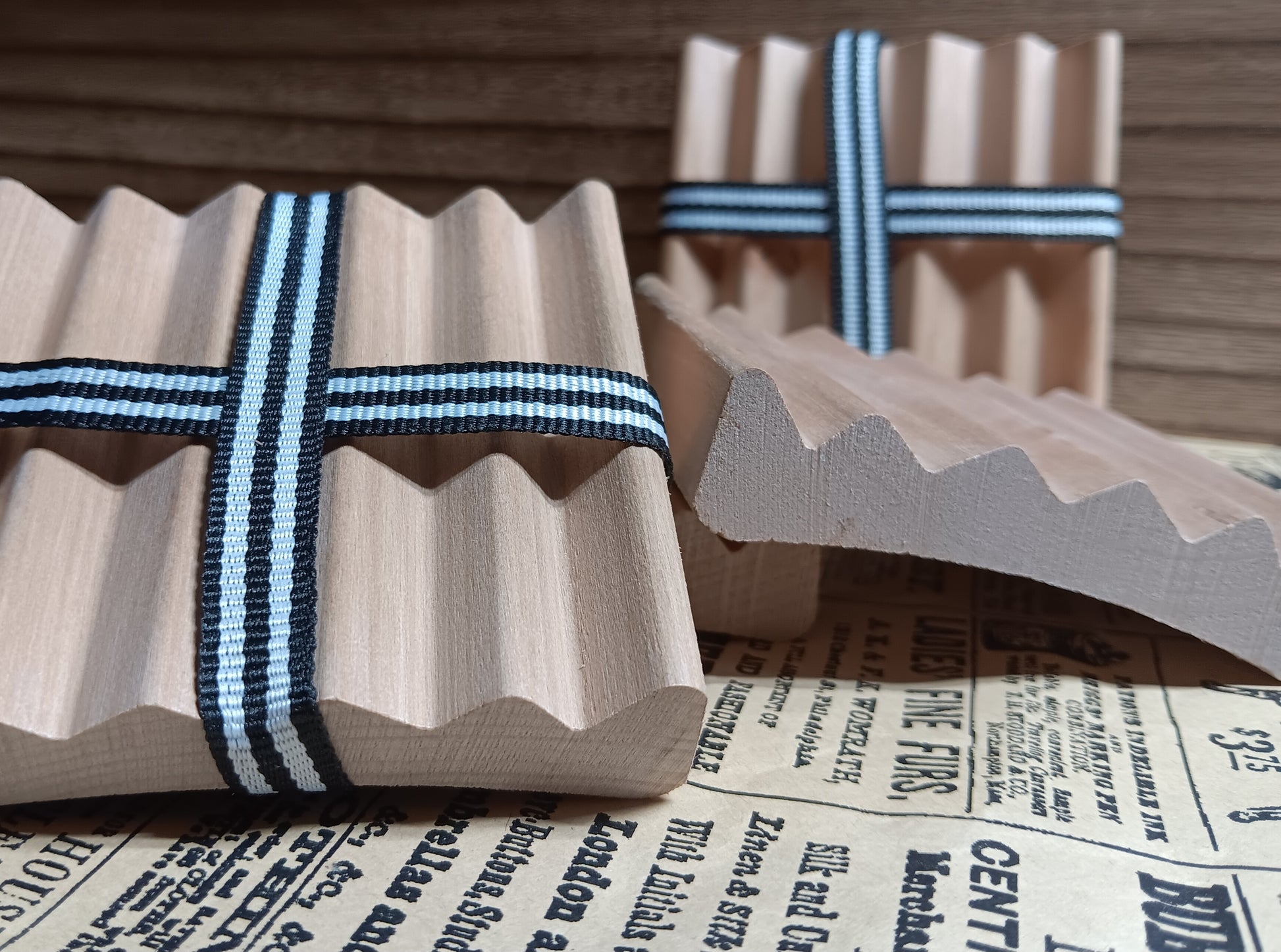 Wooden red alder soap dishes ribbons on a newspaper background