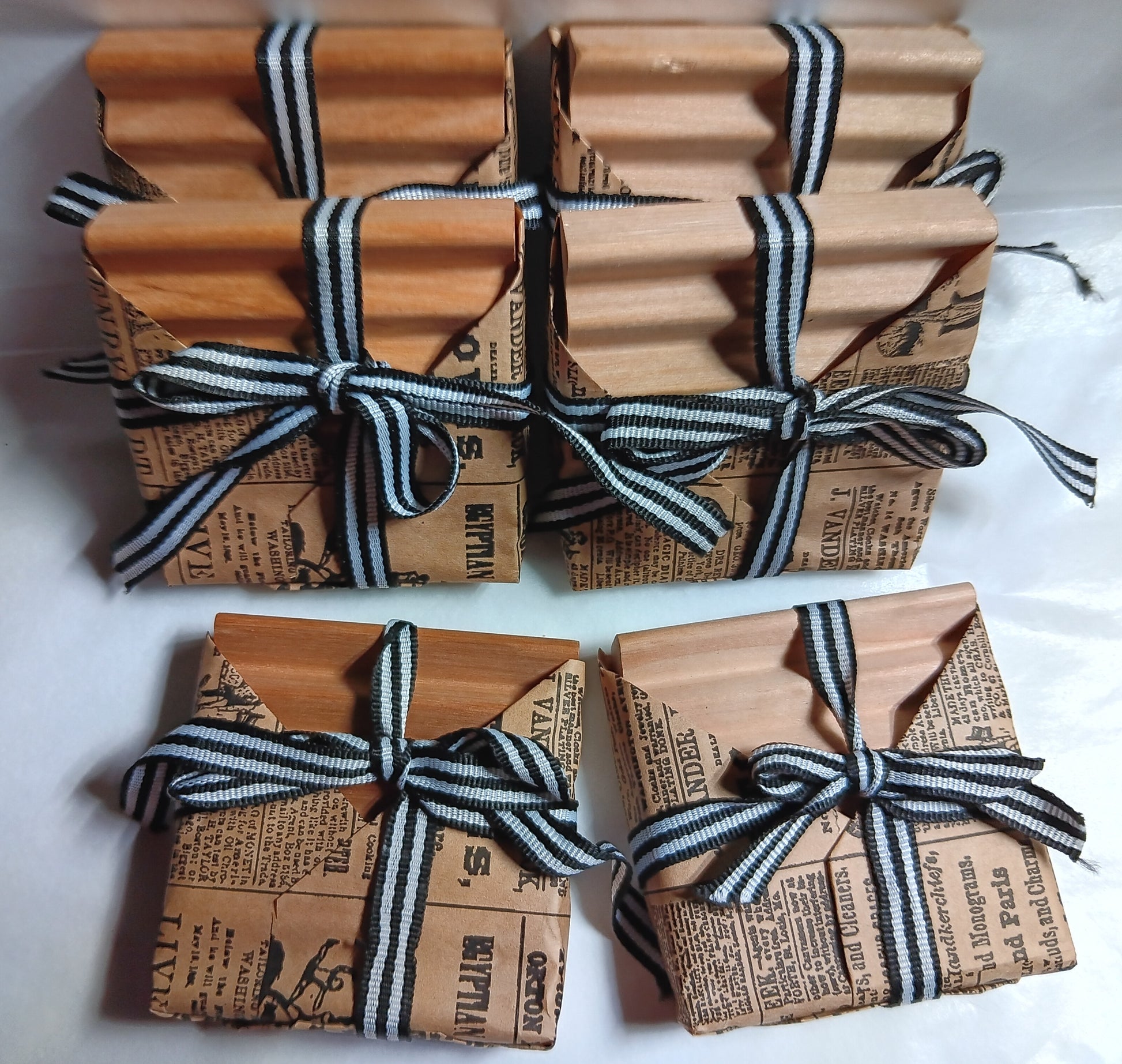 Wholesale case wrapped soap dishes with newspaper-style wrapping and black and white ribbons on a white background